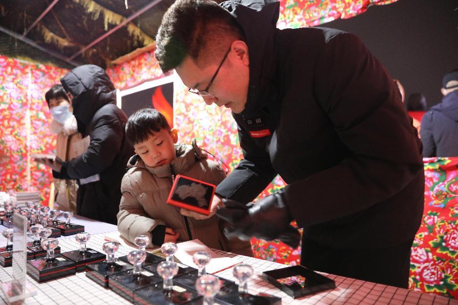 “东津雪景庙会嘉年华”活动上，市民带着孩子在制作城市文旅印章本。